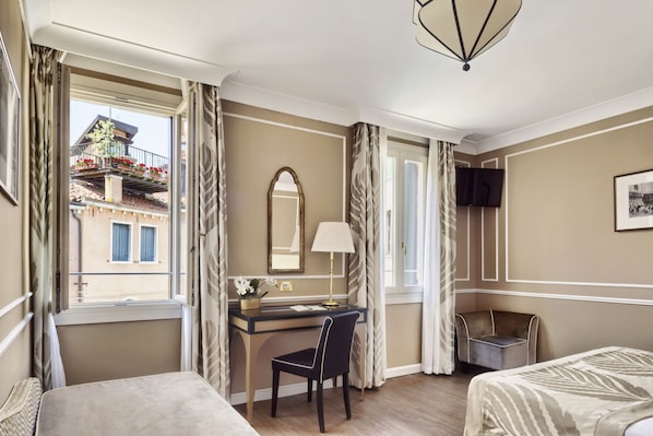 A hotel room with a bed, a desk with a chair, a TV, and a window with curtains. - Hotel Al Nuovo Teson (Venice)