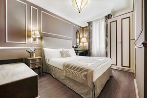 Una camera d'albergo con un letto grande, comodini, una scrivania e un armadio.