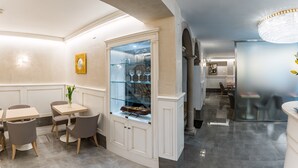 A modern dining area with a glass display case, marble flooring, and a chandelier. - Hotel Guerrini (Venice)