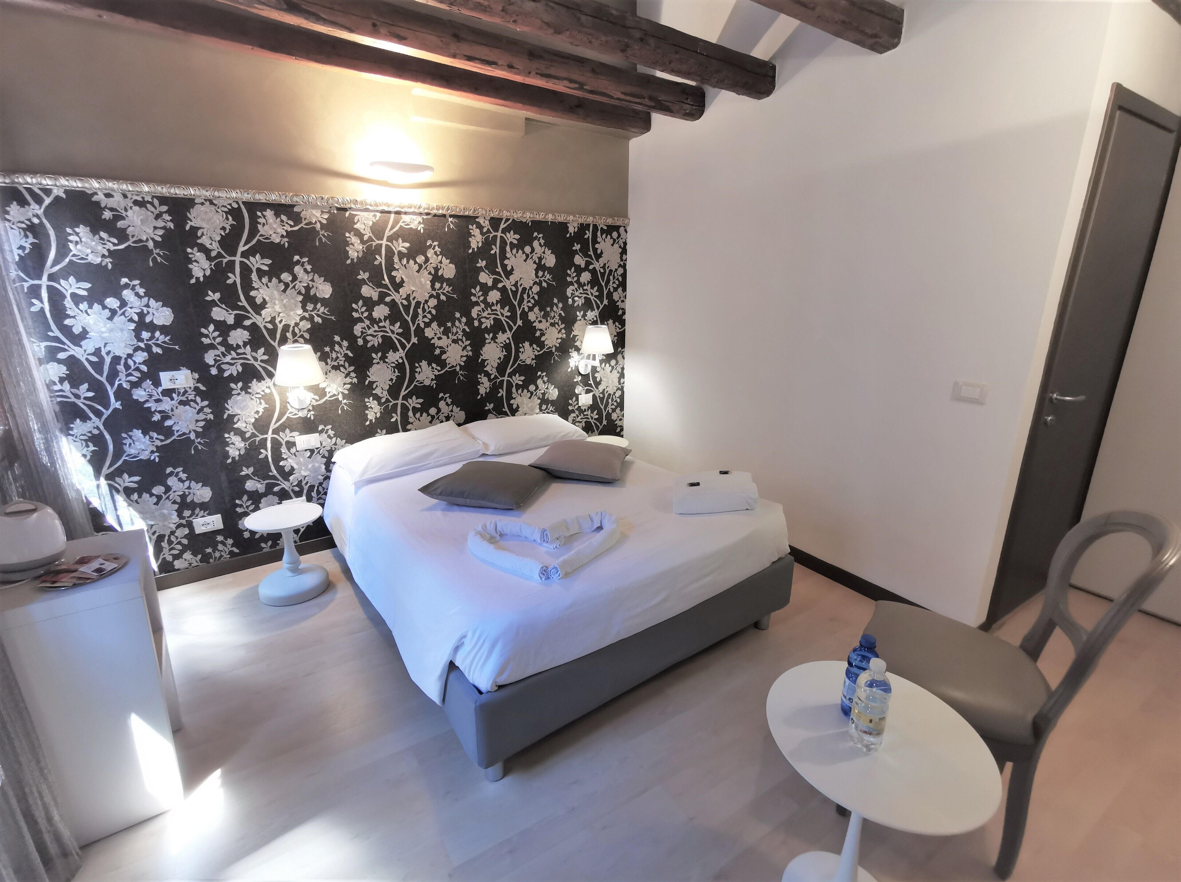 A bedroom with a bed, bedside lamps, a small table, and a chair.