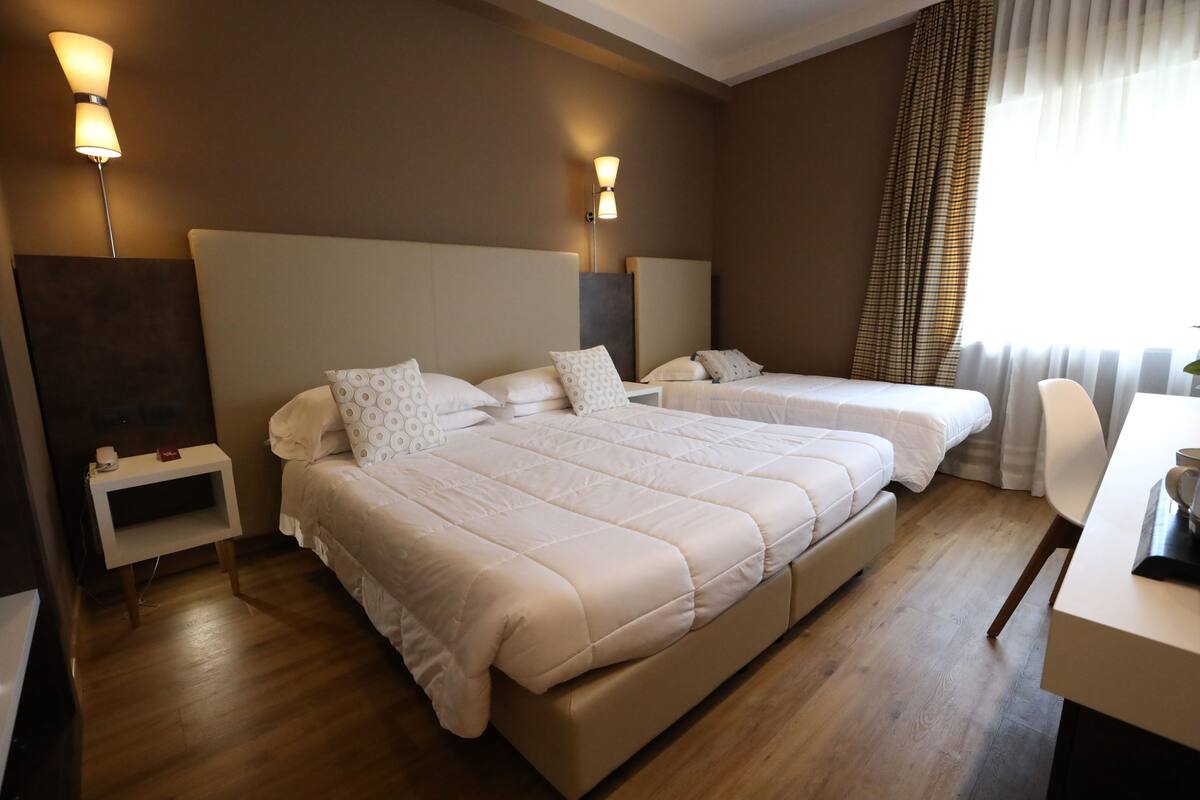 Une chambre d’hôtel avec deux lits, une table de chevet, un bureau et une chaise.