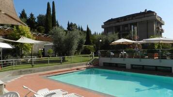 Relax by the pool surrounded by lush greenery and comfortable lounge chairs.