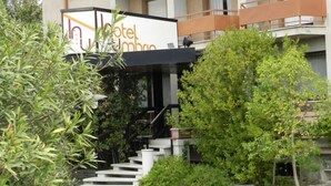 A hotel entrance with a staircase leading to the entrance, surrounded by greenery and a stone-paved area. - Umbria (Attigliano)