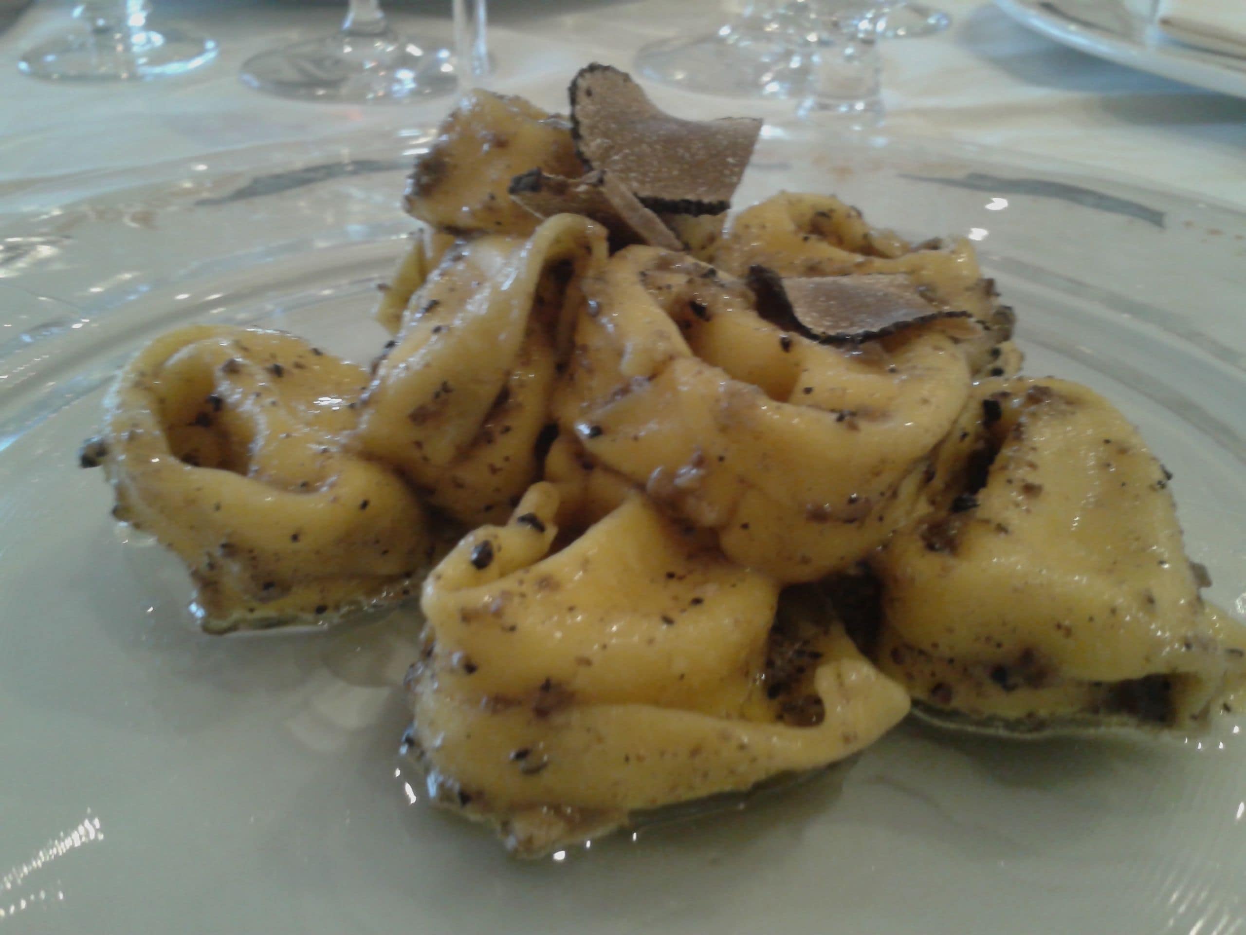 A plate of ravioli with a creamy sauce and a piece of chocolate on top.