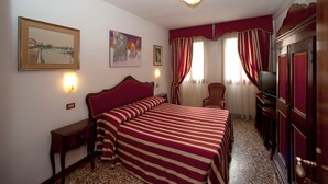 A hotel room with a large bed, a television, a desk, and a chair. - Hotel Fontana (Venice)