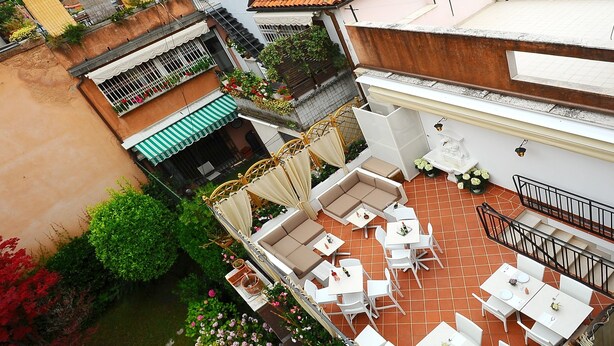 A courtyard with outdoor seating, surrounded by buildings with historical architecture. - Hotel Fontana (Venice)