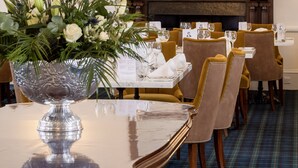 Un comedor elegante con un espejo grande, candelabros ornamentados y un centro de mesa floral sobre la mesa.