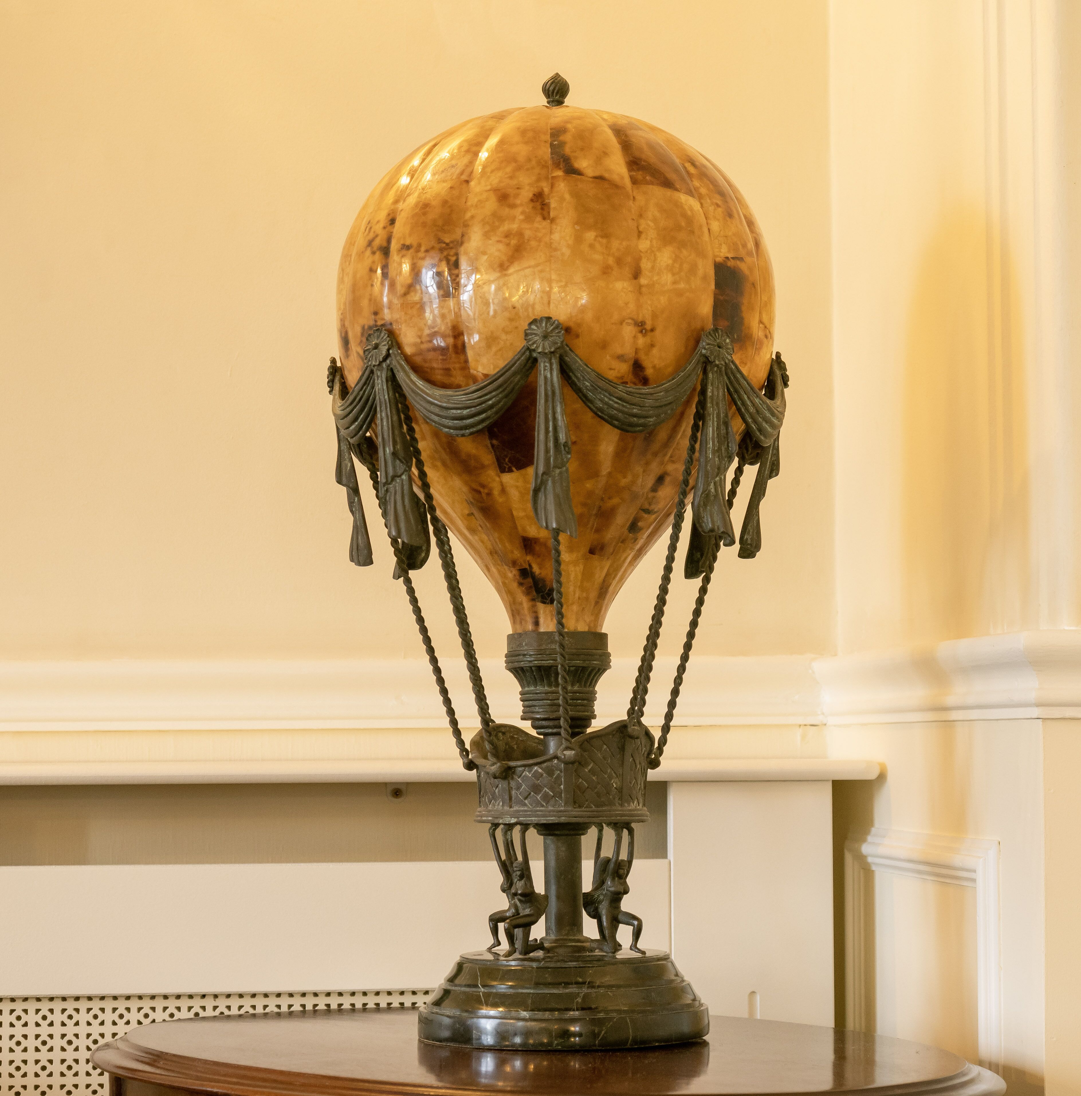 A globe with a decorative base and draped fabric.