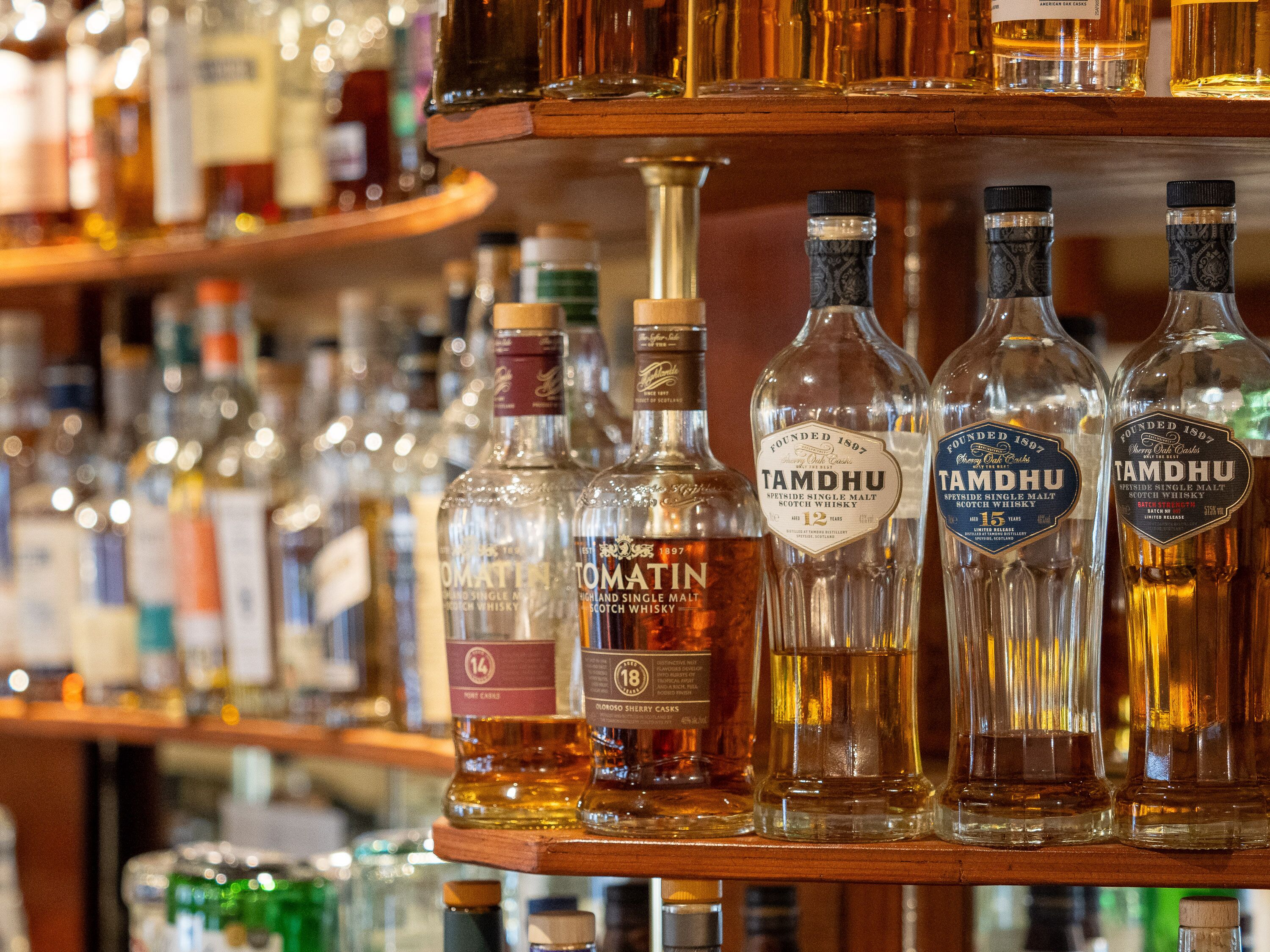 Variedad de botellas de whisky en estanterías en un bar.