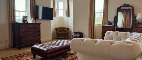 Een ruime kamer met een groot bed, een houten dressoir, een televisie en een kroonluchter.
