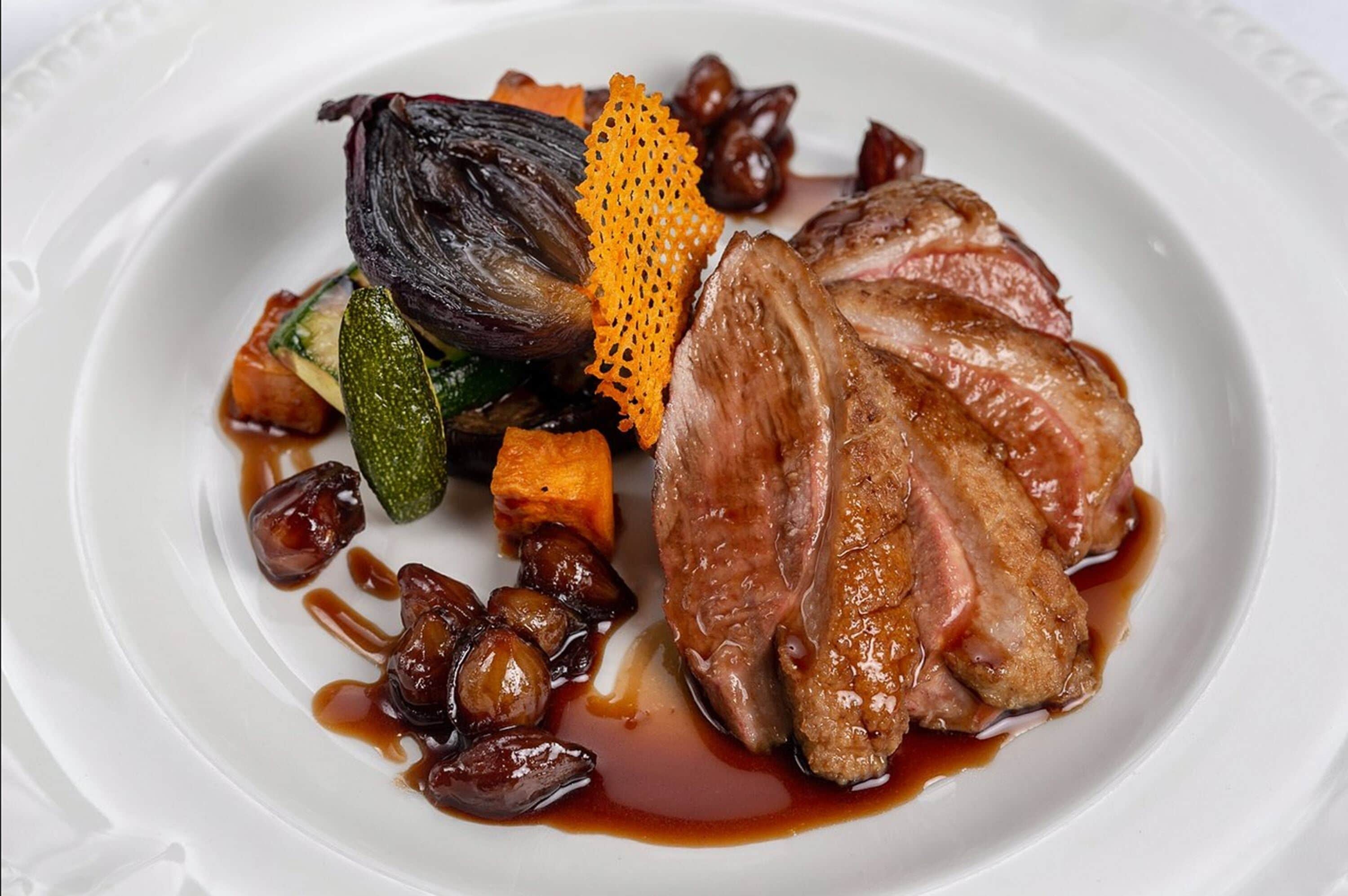 Un plato de comida con carne, verduras y un adorno.
