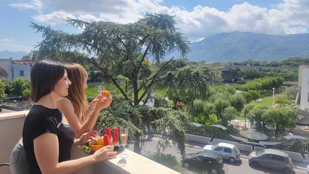 En balkon med udsigt til en vej, biler og et bjerglandskab.