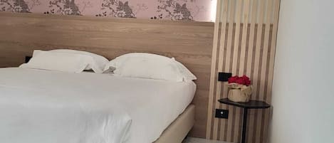 Una camera da letto con un letto, un comodino e un tavolino con una borsa sopra.