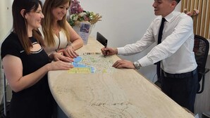 En moderne reception med skærm, blomstervase og et kort på disken.