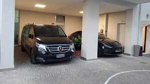 En parkeringsplads med to sorte Mercedes-Benz biler parkeret under et tag.