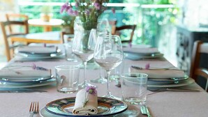 A dining table set with plates, glasses, and cutlery, with a vase of flowers in the center. - Villa Rosa Panzano (Greve in Chianti)