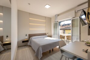 Una habitación de hotel moderna con cama, mesita de noche y vistas al balcón exterior.