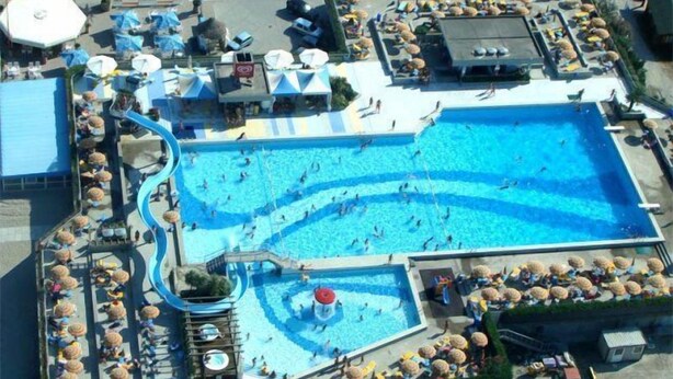 A large outdoor swimming pool with multiple lanes, surrounded by sun loungers and umbrellas. - Sole (Rosolina)