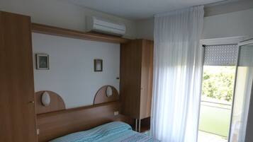 Une chambre à coucher comprenant un lit, une armoire et une porte-fenêtre coulissante donnant sur un balcon.