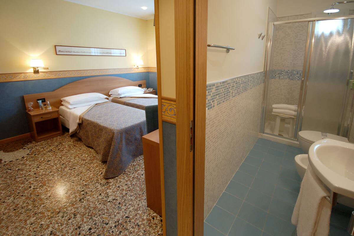 Una habitación de hotel con dos camas, ducha y baño.