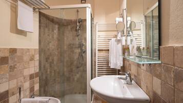 Un bagno con doccia vetrata, un lavandino bianco e uno specchio sopra.