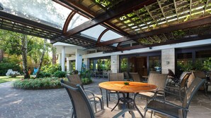 An outdoor patio with a round table and chairs, surrounded by stone flooring and greenery. - Columbia (Ravenna)