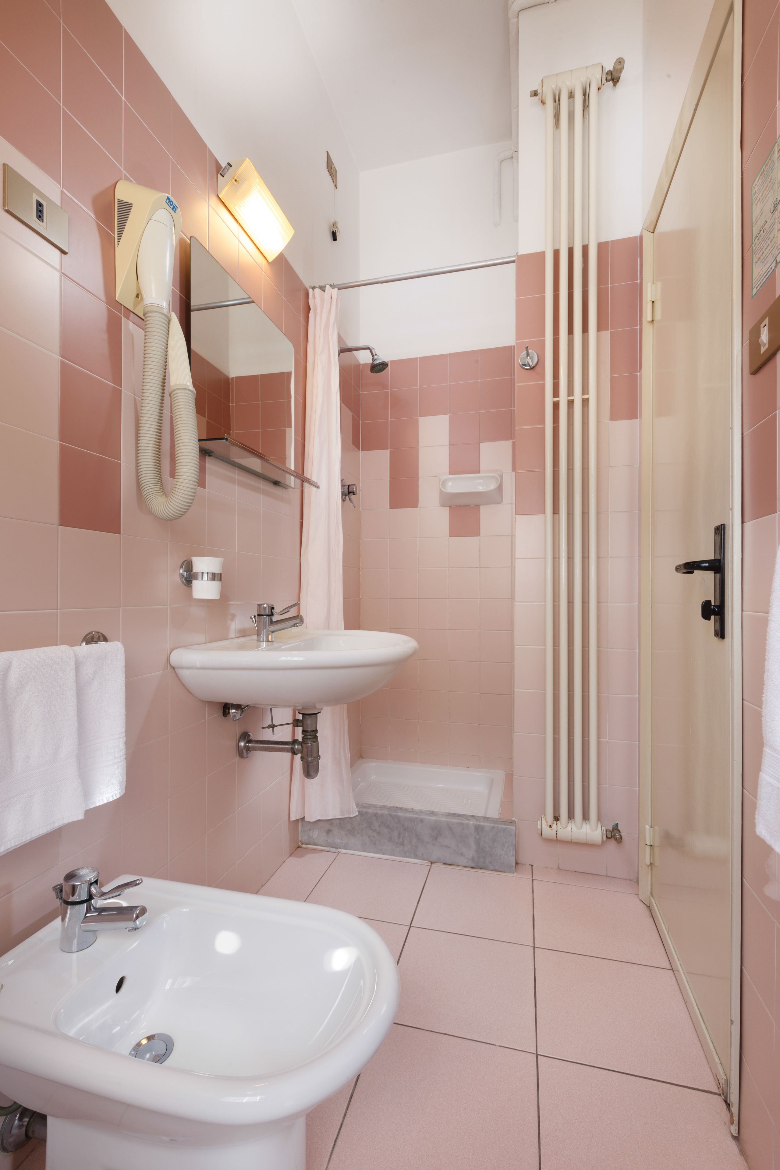 A bathroom with a sink, mirror, and shower.