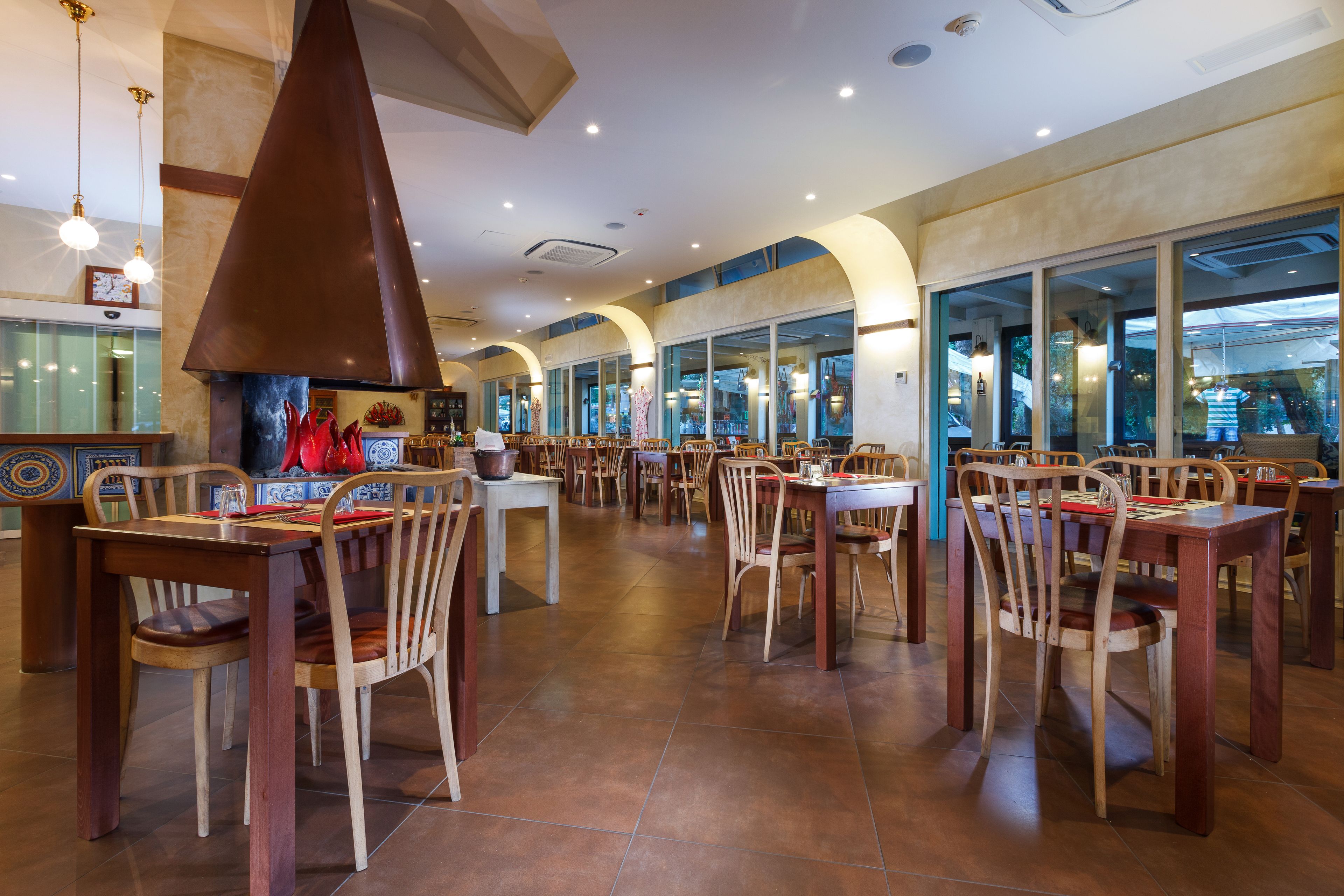 A spacious restaurant with high ceilings, large windows, and a variety of wooden tables and chairs.