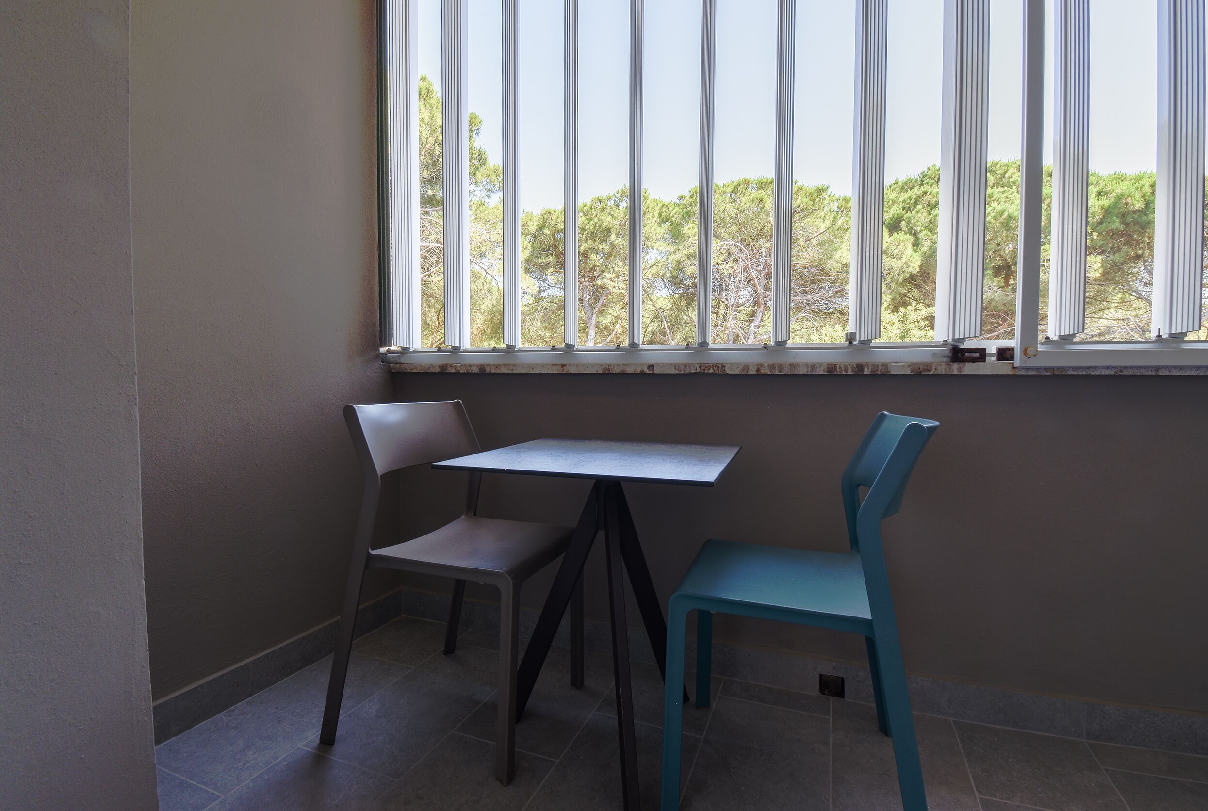 A small room with a window, a table, and two chairs.