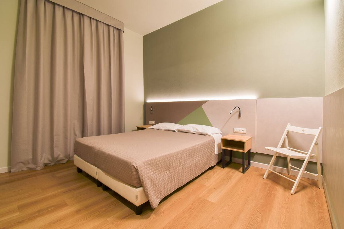A neatly arranged bedroom with a bed, bedside tables, and a chair.