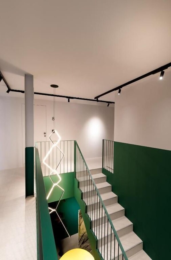 A staircase with a green accent wall, a modern light fixture, and a number '8' sign.