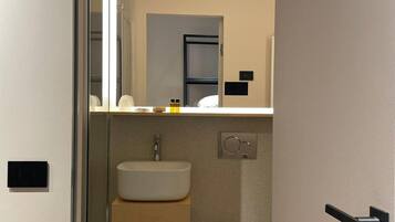 A compact bathroom with a sink, toilet, and a trash bin.