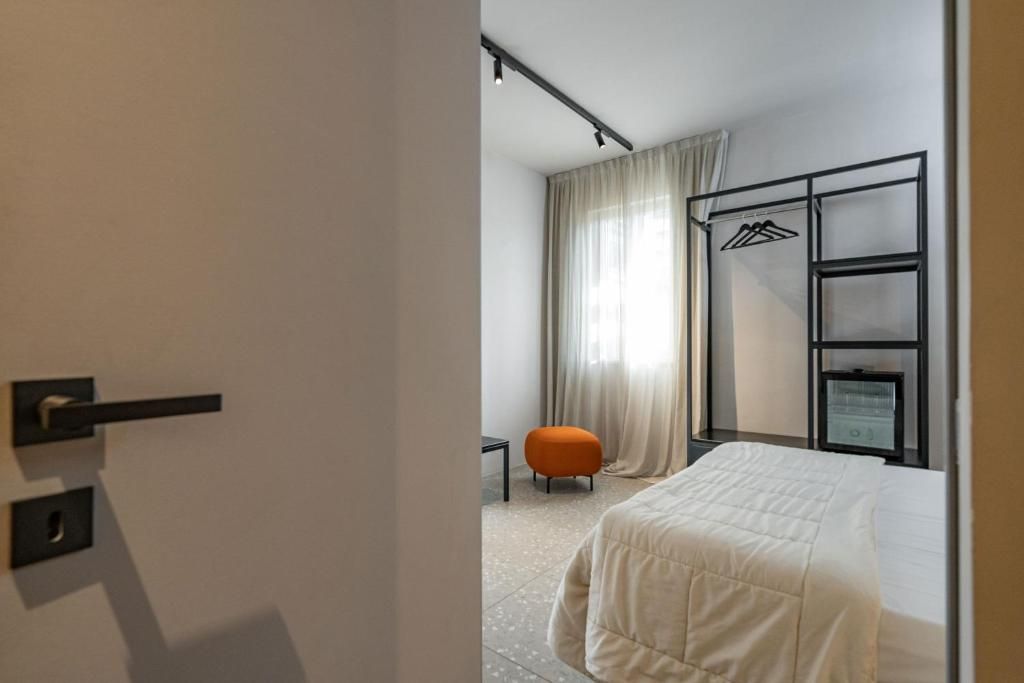Une chambre d’hôtel avec un lit, une chaise, une armoire et une fenêtre avec des rideaux.