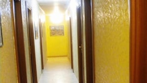 A hallway with yellow walls and a tiled floor, leading to a door at the end. - Hotel Casanova (Naples)