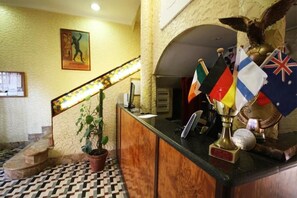A reception desk with multiple flags, a trophy, and a golden eagle statue. - Hotel Casanova (Naples)
