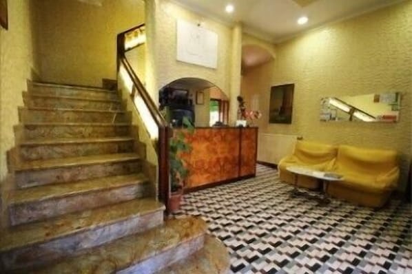 A staircase leading to a reception area with a check-in counter, a sofa, and a patterned floor. - Hotel Casanova (Naples)