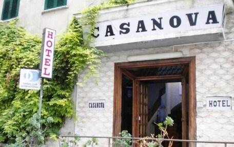 A hotel named CASANOVA with a stone facade, a wooden entrance, and potted plants outside.
