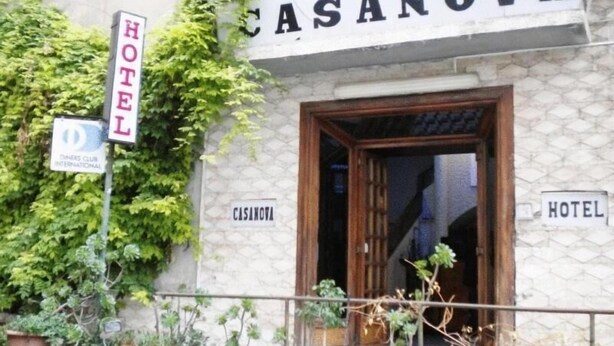 A hotel named CASANOVA with a stone facade, a wooden entrance, and potted plants outside. - Hotel Casanova (Naples)