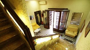 A staircase leading to a room with a checkered floor, a wooden cabinet, and a yellow armchair. - Hotel Casanova (Naples)