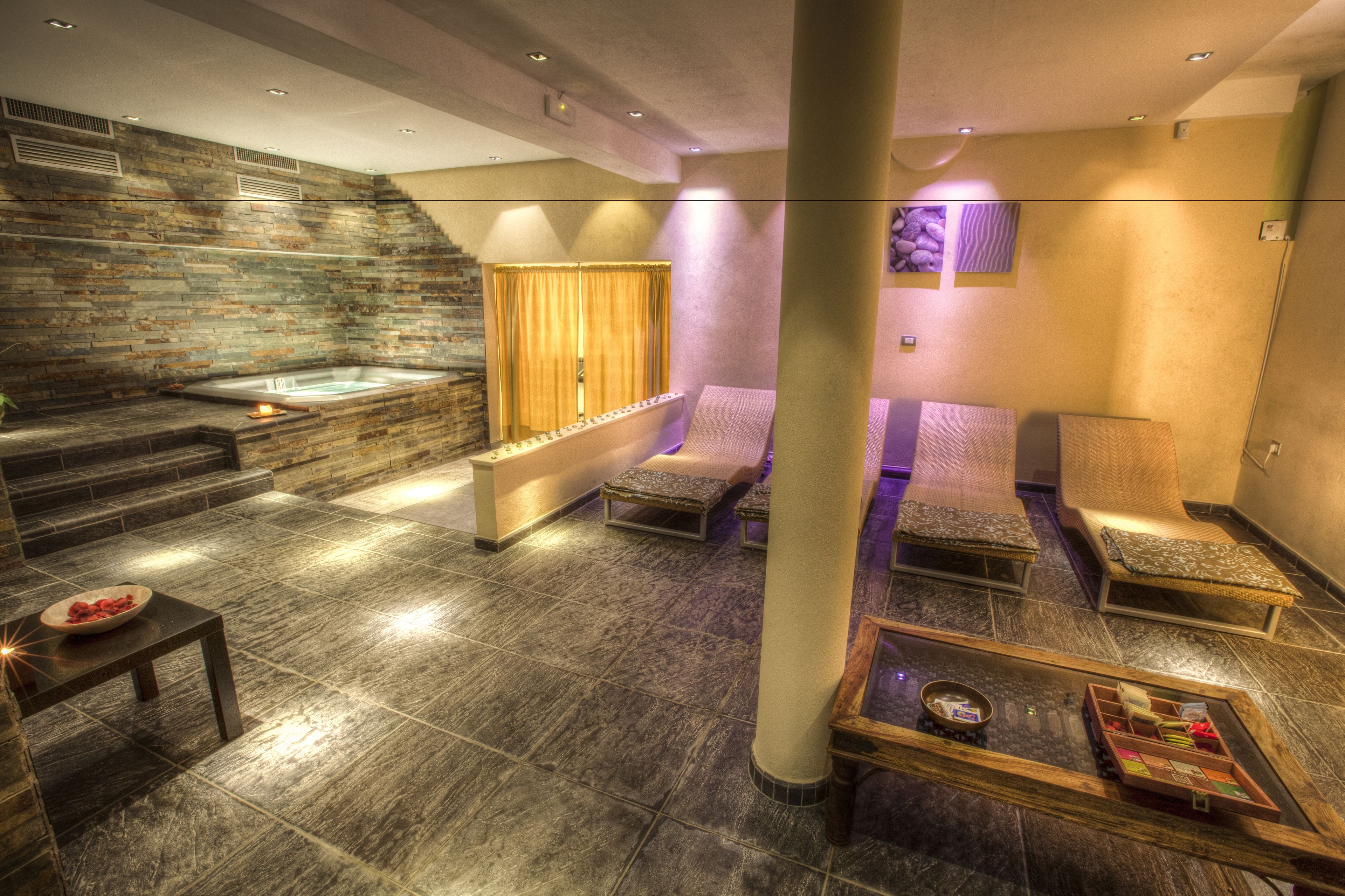 A spa area with a stone wall, a hot tub, and seating areas.