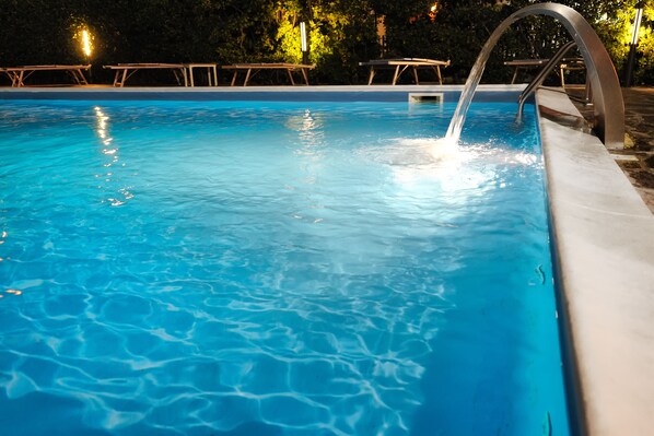 Una piscina con agua cristalina azul, borde metálico y un desagüe.