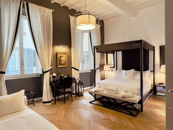 A four-poster bed with a canopy, a desk with a chair, and a small table with a lamp. - Relais Uffizi, Tailor made Hotel (Florence)