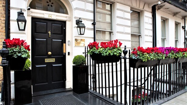 A black door with a brass plate, number 54, and a small potted plant beside it. - The Sumner (London)