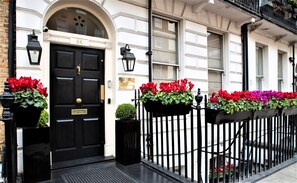 A black door with a brass plate, number 54, and a small potted plant beside it. - The Sumner (London)