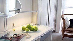 A modern bathroom with a white vanity, a round mirror, and a plate of green apples on the counter. - The Sumner (London)