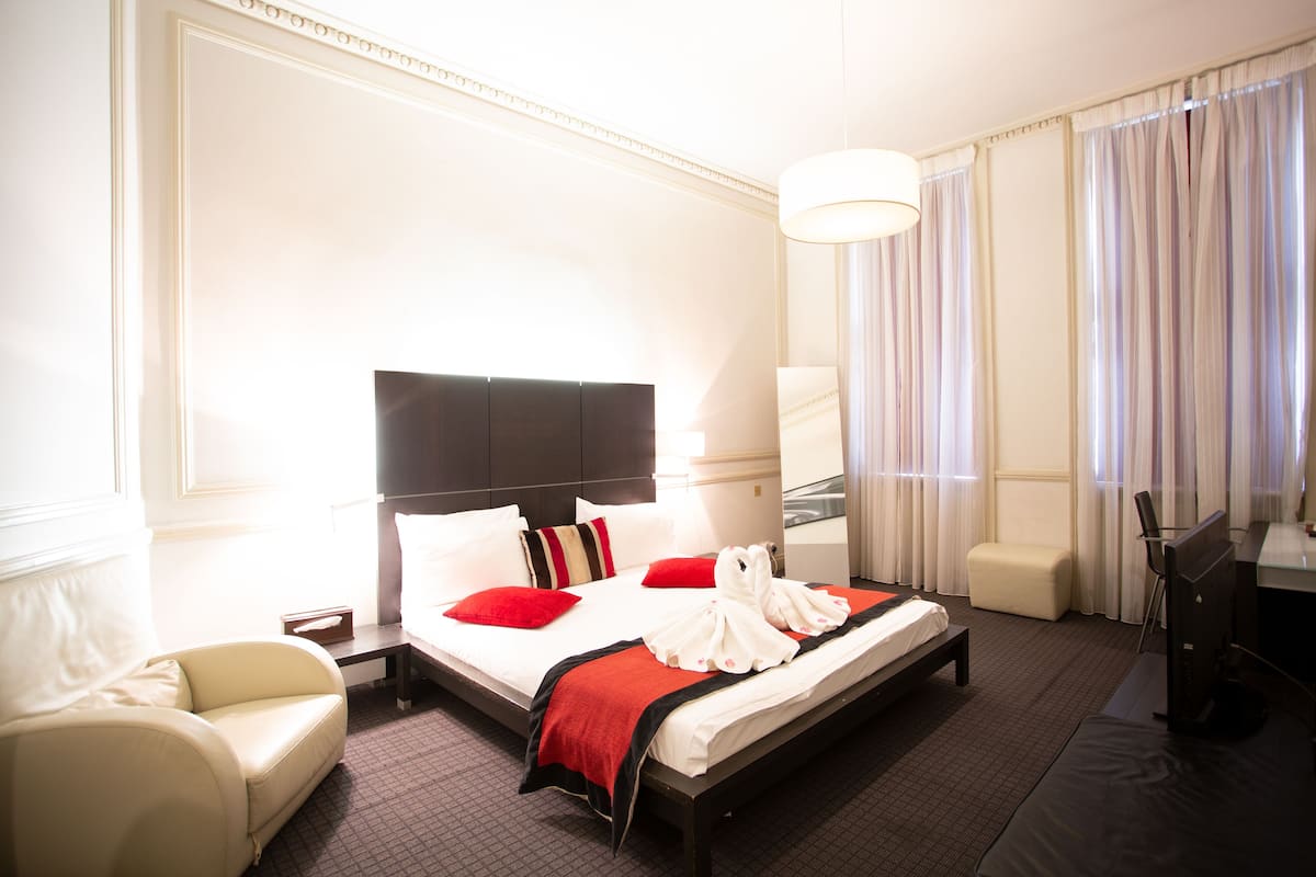 Ein Hotelzimmer mit einem großen Bett, einem Schreibtisch, einem Stuhl und einer Lampe.