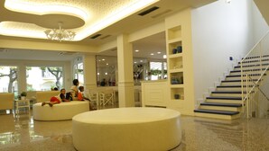 A spacious lobby with a central seating area, a staircase, and a reception desk. - Hotel Sport & Residenza (Cesenatico)