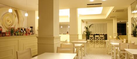 Un hall de hotel con barra central, varios arreglos de asientos y una gran pared decorativa.