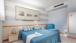 A bedroom with a bed, bedside tables, a chair, and a framed picture on the wall. - Hotel Sport & Residenza (Cesenatico)