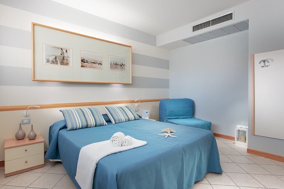A bedroom with a bed, bedside tables, a chair, and a framed picture on the wall.